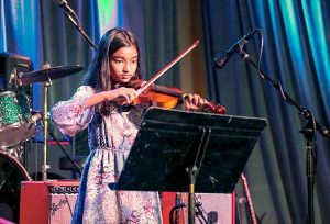 female student plays violin in recital