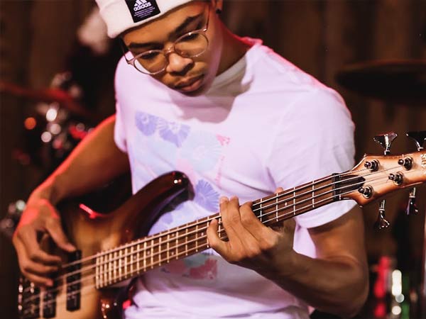 Male student plays bass guitar on stage