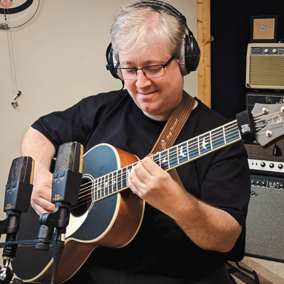 Man plays guitar in recording studio