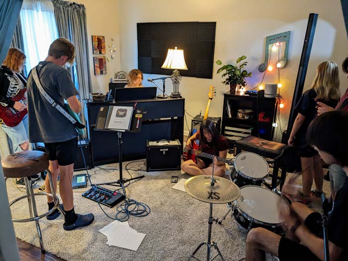 Student rock band rehearses in a music room with instruments