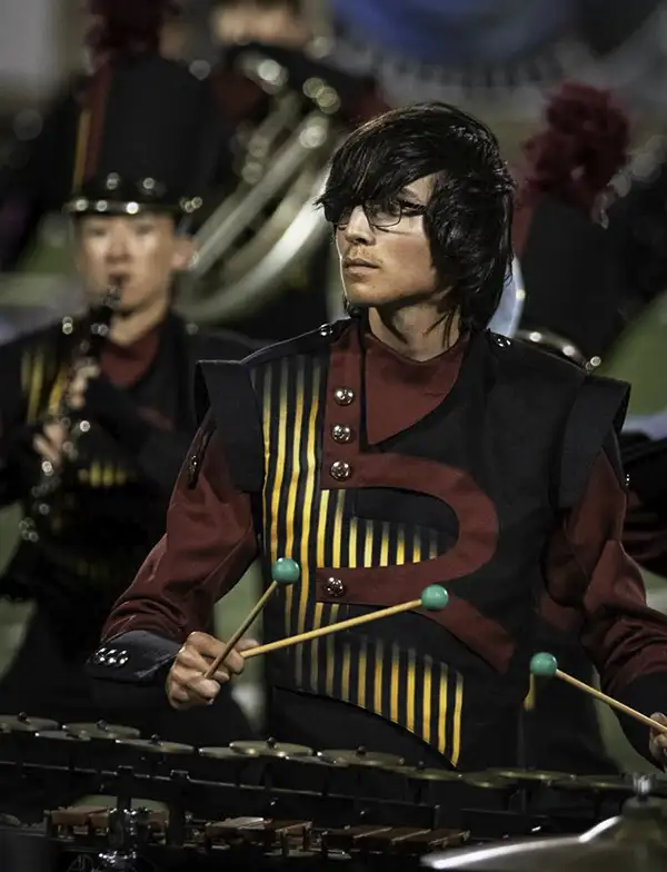 Teen boy playing percussion in a marching band uniform