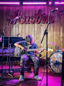 young buy plays guitar in music school recital