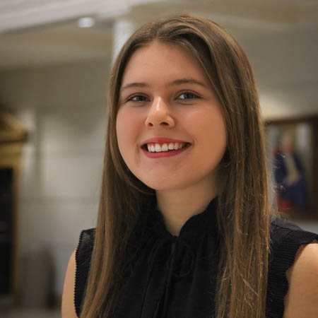 Young woman with long brown hair smiles at camera