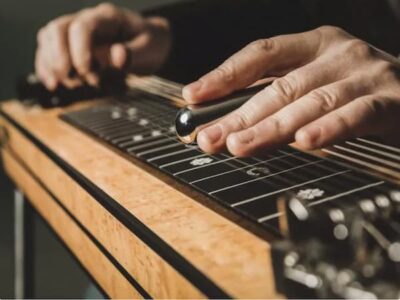 closeup of man's hand holding a slide playing a pedal steel guitar
